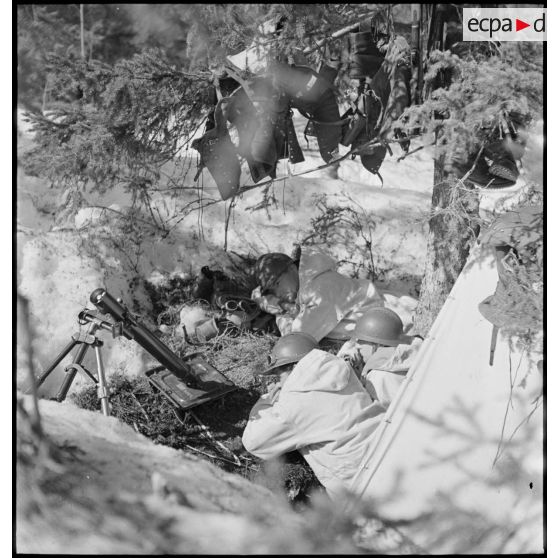 Des chasseurs alpins de la 1ère DLCh (Division légère de chasseurs), servants d'un mortier Stokes-Brandt de 81 mm, sont postés en position de tir dans un trou de combat.