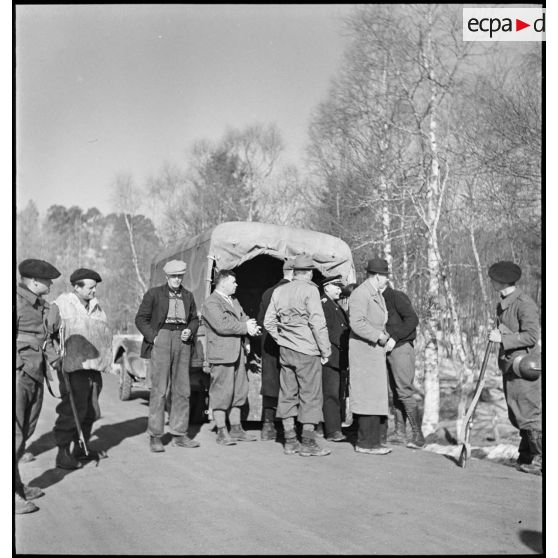 Civils norvégiens et soldats français derrière un véhicule de transport.