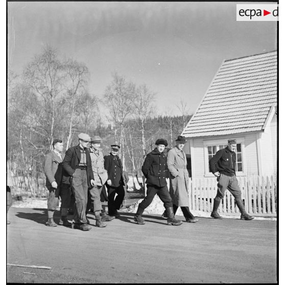 Des civils norvégiens et des soldats français circulent à pied sur une route.