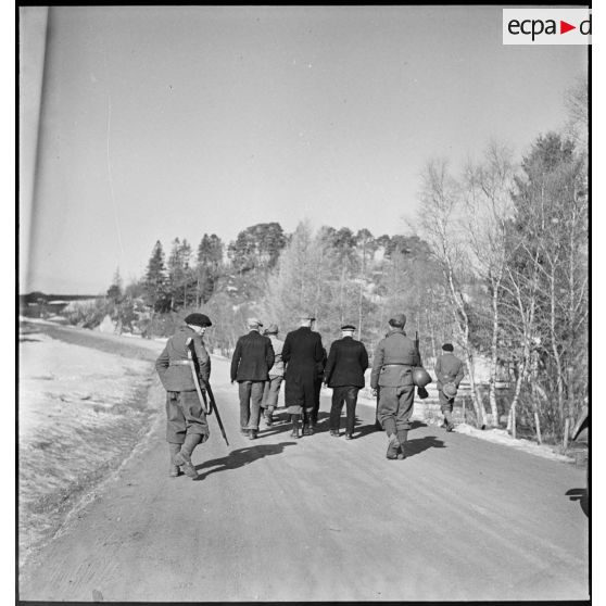 Des civils norvégiens et des soldats français circulent à pied sur une route.