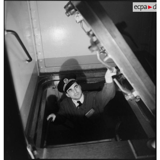 Alerte à bord du cuirassé Dunkerque : un enseigne de vaisseau, chef de zone, ferme un panneau d'accès.