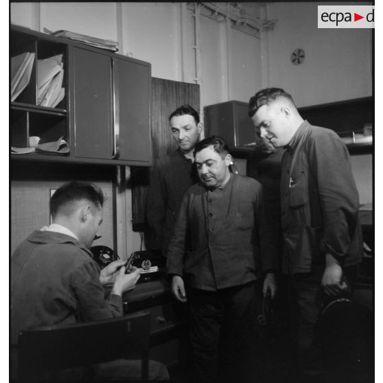 Des officiers mariniers présentent une pièce à un lieutenant de vaisseau du compartiment des machines du cuirassé Dunkerque.