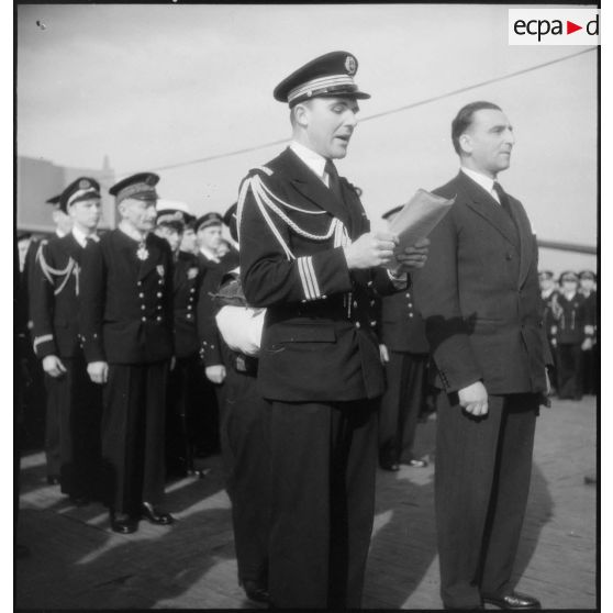 Un lieutenant de vaisseau lit l'ordre du jour lors d'une cérémonie présidée par Louis Jacquinot, ministre de la Marine.