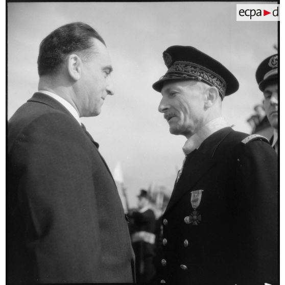 Louis Jacquinot, ministre de la Marine, félicite le contre-amiral Robert Jaujard auquel il vient de remettre l'insigne de commandeur de la Légion d'honneur lors d'une cérémonie à bord d'un bâtiment.