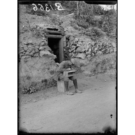 Ravin de Brimont (Oise). Devant une cagna, un soldat fait son courrier. [légende d'origine]