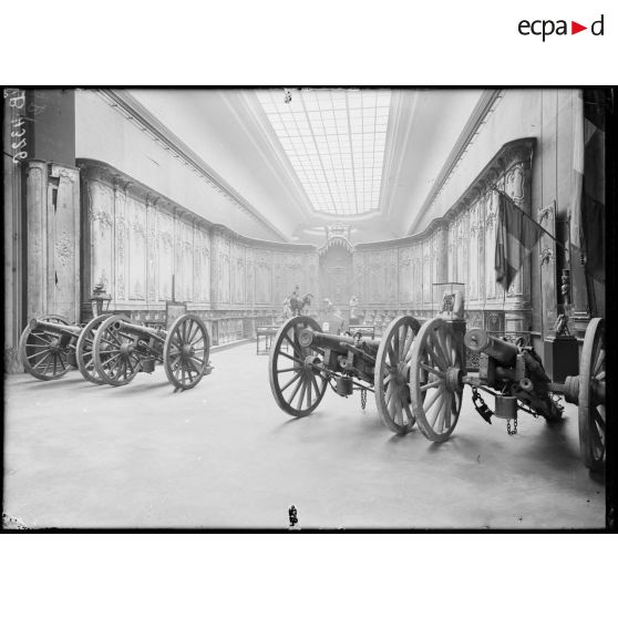 Petit Palais, exposition des œuvres d’arts mutilés, les boiseries de la catéhdrale de Verdun, époque Louis XV, au 1er plan, les canons donnés à Verdun en souvenir de la belle conduite des habitants pendant le siège de 1870. [légende d’origine]
