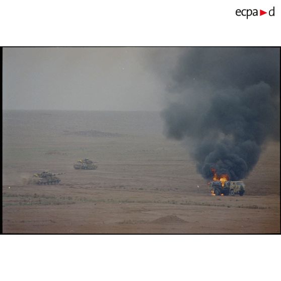 Des chars AMX-30 B2 du 4e RD (régiment de dragons) progressent en bordure de l'axe Texas et dépassent un camion-citerne irakien en feu. Les chars portent des panneaux d'identification air-sol allié.