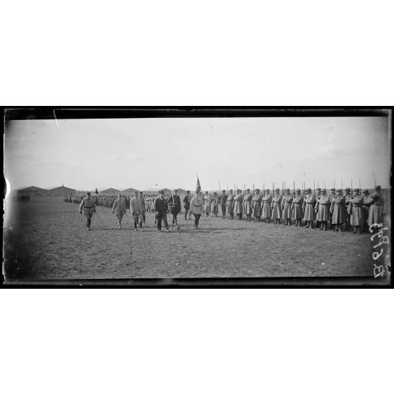 Camp d'Avord. Cérémonie en l'honneur du capitaine aviateur Guynemer. Arrivée de monsieur Dumesnil, sous-secrétaire d'Etat à l'aviation et des généraux Meunier et Muteaux et du colonel Girod. Le cortège passe devant le groupe d'artillerie. [légende d'origine]