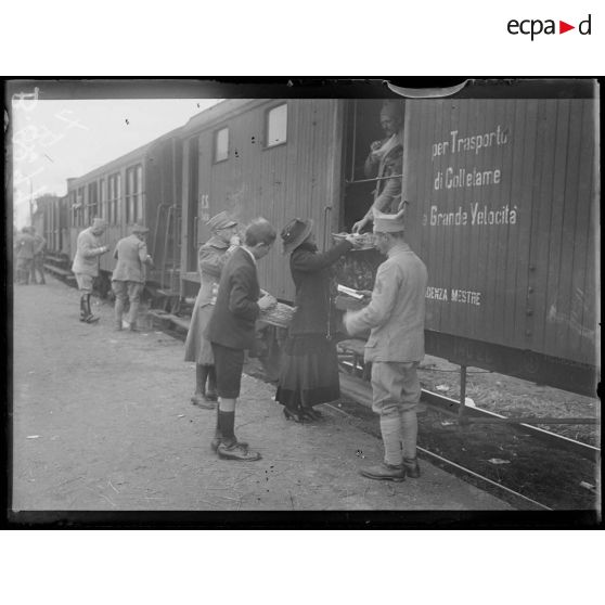 Près Milan. Passage d'un train de troupes françaises. Dame italienne offrant des friandises aux soldats. [légende d'origine]