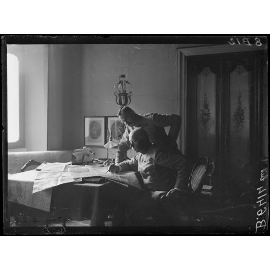 [Deux officiers consultent une carte dans un bureau.]