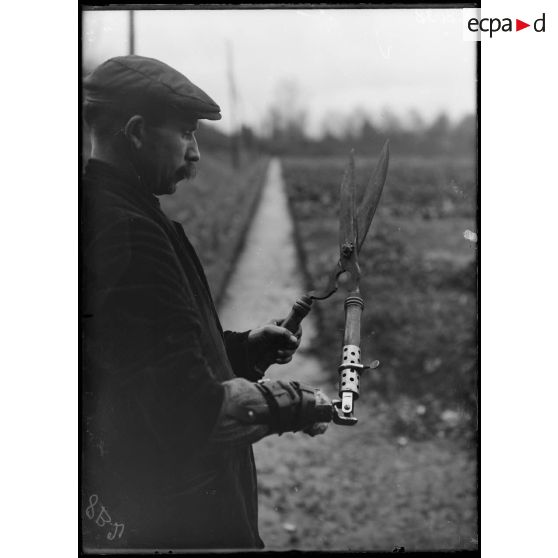 Maison-Blanche (Seine). Rééducation des mutilés cultivateurs. Cultivateur tenant des cisailles grâce au porte-outil Julien. [légende d'origine]