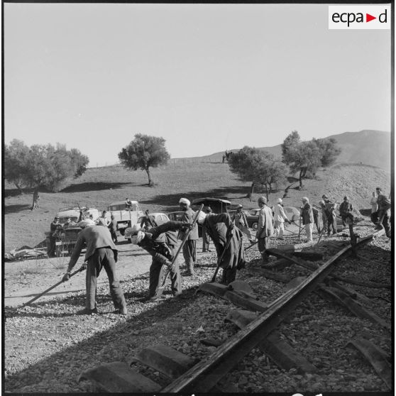 Des civils aident au remblaiement du ballast.