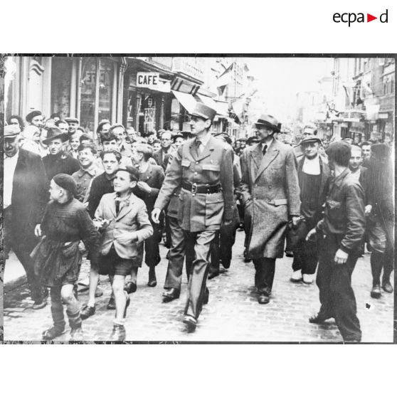 Au cours de son voyage en Normandie, le général de Gaulle salue la population de Bayeux qui l'acclame. Il est notamment accompagné par Pierre Viénot.