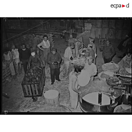 Des boulangers militaires s'affairent près des pétrins.