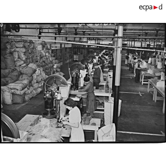 Plan général d'un atelier de découpe. Les ouvrières découpent des formes de chaussures sur des feuilles de cuir.