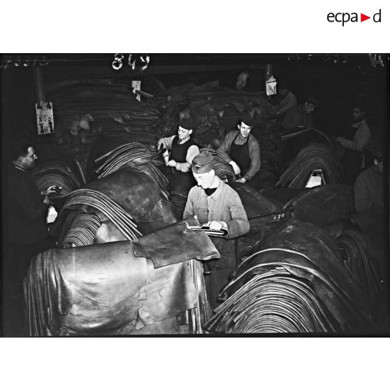Des ouvriers s'activent dans l'entrepôt de feuilles de cuir de l'usine de chaussures.