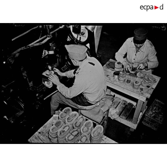 Deux ouvriers fabriquent des talons de chaussures. Ils sont photographiés en plan moyen.