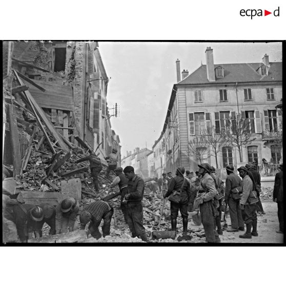 Des civils et des hommes de la défense passive évacuent les gravats d'une maison détruite par le bombardement allemand sur la ville de Nancy.