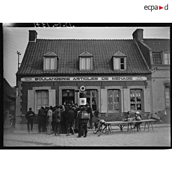 Dans un village des réfugiés se sont regroupés à l'entrée d'une boulangerie.
