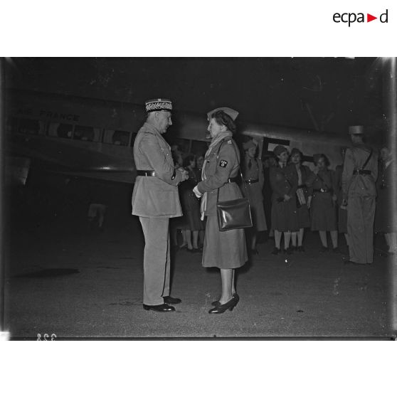 Madame Paul Reynaud discute avec le médecin général Corbec sur la piste de l'aéroport.