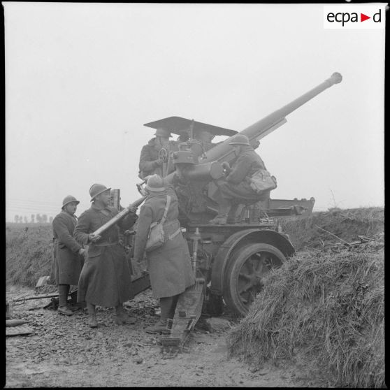 Des soldats approvisionnent un canon de 75 mm CA modèle 1917/34 sur remorque avec un obus modèle 28.