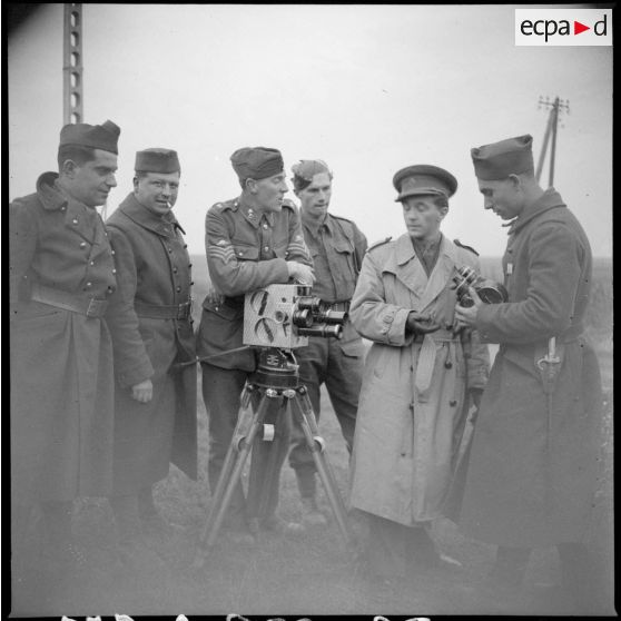 Un caméraman anglais s'appuie sur sa caméra, il est entouré de soldats.
