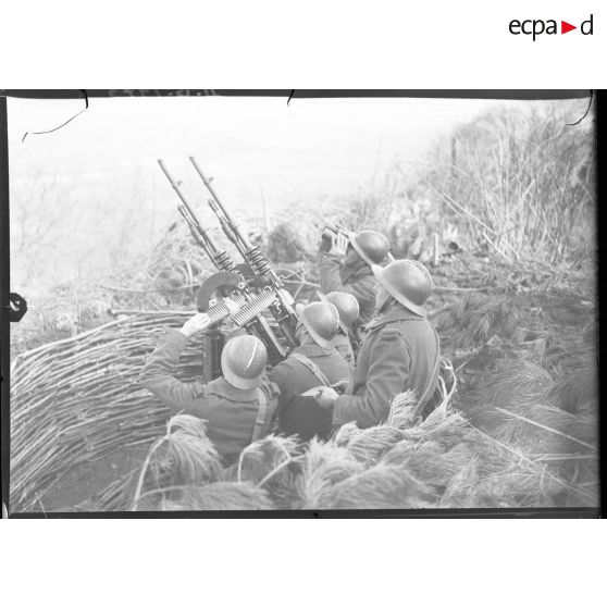 Des soldats servent des mitrailleuses Hotchkiss modèle 1914 jumelées sur affût double de marine.