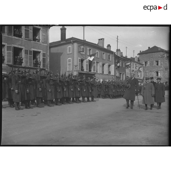 Monsieur Vanier, ambassadeur du Canada, et le général d'armée Réquin passent des troupes en revue sur une place de village.
