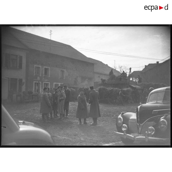 Photographie de groupe de l'ambassadeur du Canada en France, Monsieur Vanier, et du général d'armée Réquin accompagnés de diverses personnalités dans une cour de ferme.