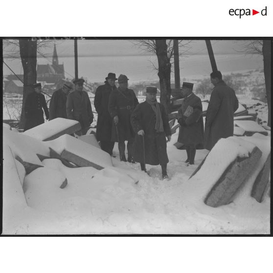 Photographie de groupe de l'ambassadeur du Canada en France, Monsieur Vanier, et du général d'armée Réquin accompagnés de divers officiers qui marchent dans la neige lors d'une visite.