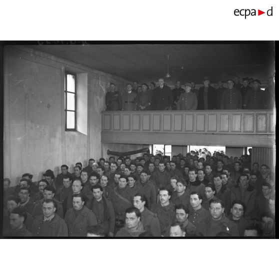 Plan général d'une assemblée de soldats, l'ambassadeur canadien et le général Réquin se tiennent en tribune.