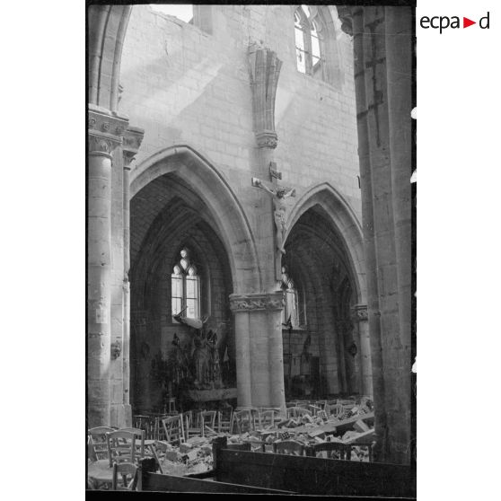 Plan moyen de la nef d'une église jonchée de débris qui proviennent de la toiture détruite par le bombardement.