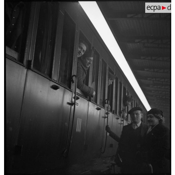 Le départ d'un train de permissionnaires, les soldats sont aux fenêtres des wagons.