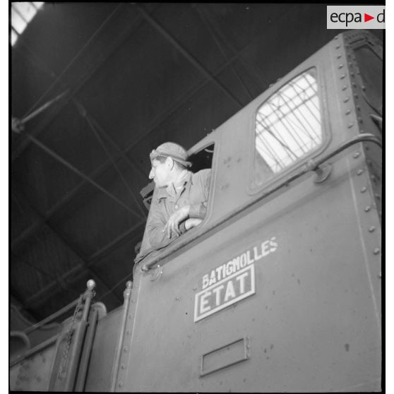 Plan moyen du chauffeur et du mécanicien qui se penchent à la fenêtre de leur locomotive.