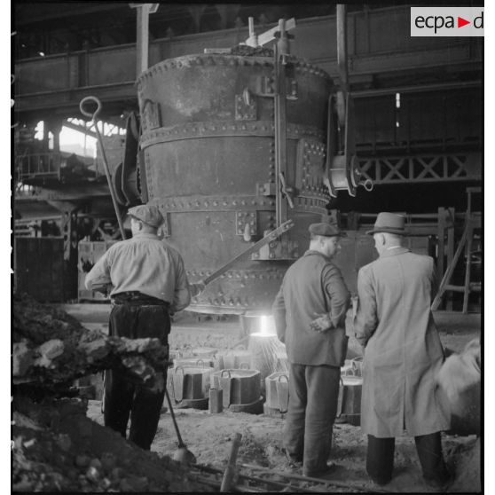 A l'intérieur de l'usine des ouvriers travaillent devant un fourneau.