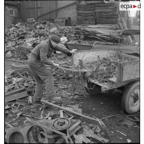 Des ouvriers effectuent un tri dans l'entassement de ferraille à l'extérieur de l'usine.