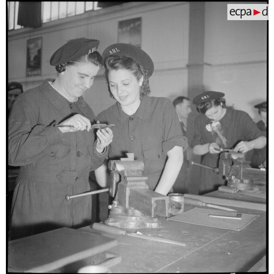 Plan américain de deux élèves féminines qui mesurent une pièce métallique avec un pied à coulisse.