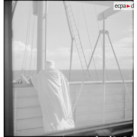 Un pèlerin, photographié de dos, est accoudé au bastingage du paquebot "Gouverneur général Gueydon" qui transporte les pèlerins vers la Mecque.