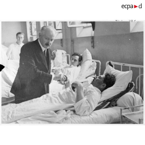 Dans un hôpital le président de la République Albert Lebrun se tient au chevet d'un blessé, victime civile d'un bombardement allemand.
