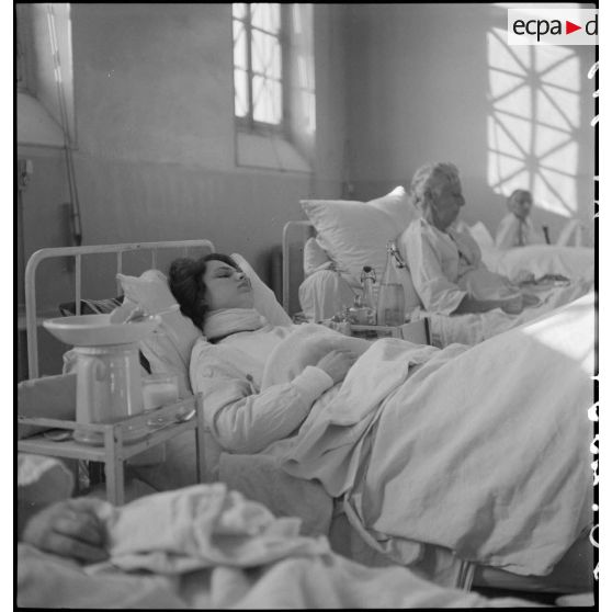 Dans un hôpital photographie de groupe de blessés alités, victimes civiles d'un bombardement allemand.