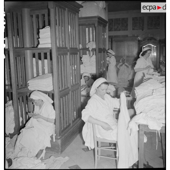 Dans une buanderie d'un hôpital des infirmières font de la charpie avec des draps.