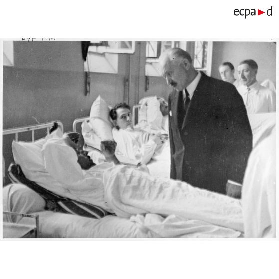 Dans un hôpital le président de la République Albert Lebrun se tient au chevet d'un blessé, victime civile d'un bombardement allemand.
