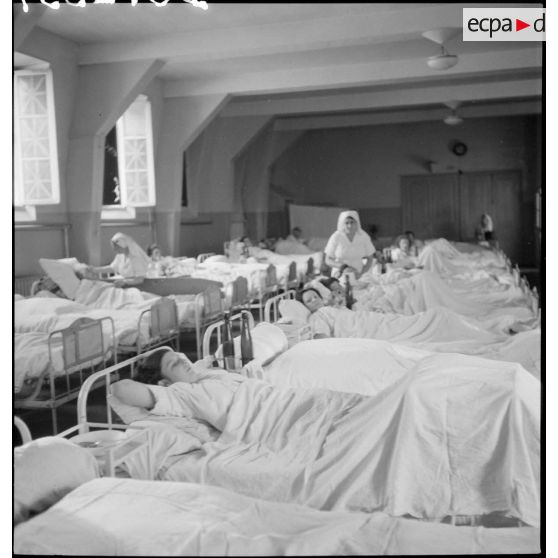 Dans un hôpital photographie de groupe de blessés alités, victimes civiles d'un bombardement allemand.
