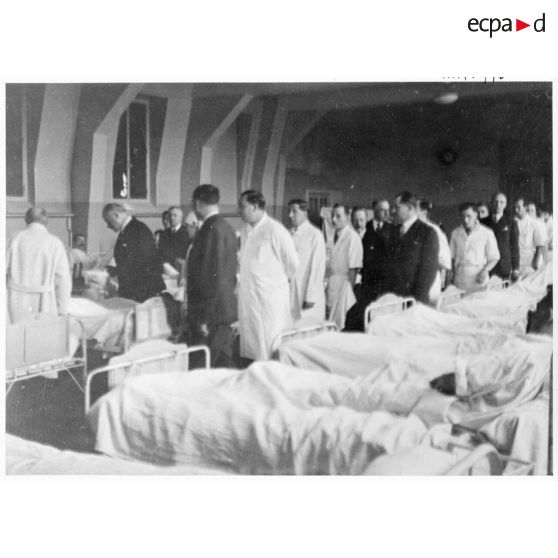 Dans un hôpital le président de la République Albert Lebrun se tient au chevet d'un blessé, victime civile d'un bombardement allemand.