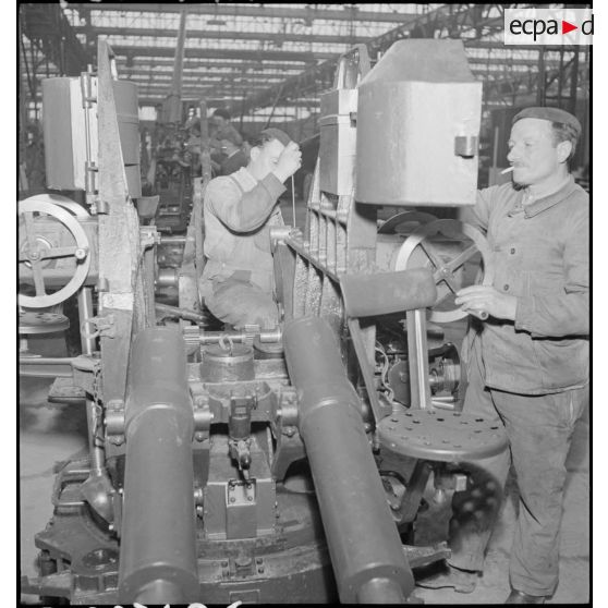 Deux ouvriers travaillent sur un affût de canon de 75 mm CA.