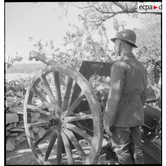 Un servant se tient près du canon de 75 mm modèle 1897.