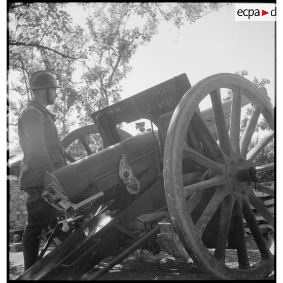 Un servant se tient près du canon de 75 mm modèle 1897.