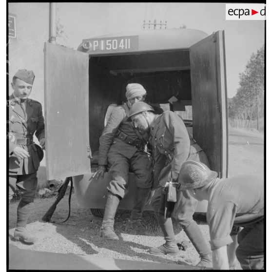 Des soldats aident un blessé du 2e RSA de la 3e BS à monter dans une ambulance.