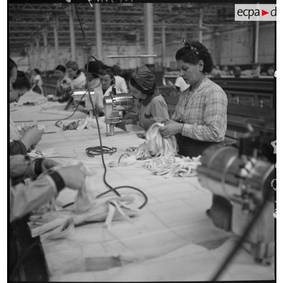 Des ouvrières et des ouvriers découpent du tissu à l'aide de patron et de machines.