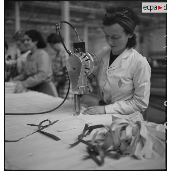 Des ouvrières et des ouvriers découpent du tissu à l'aide de patron et de machines.